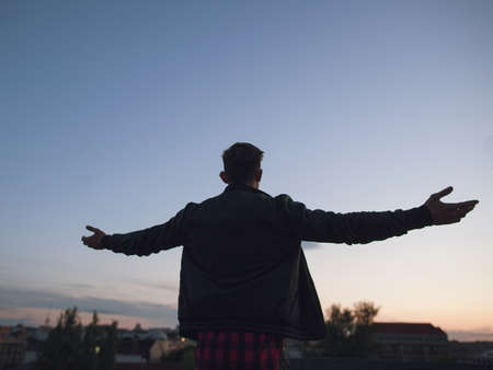 Man on top of the world. Hello world. Young male leader silhouette on blue sky background. New successful business, lonely morning, freedom and liberty in life conceptの写真素材