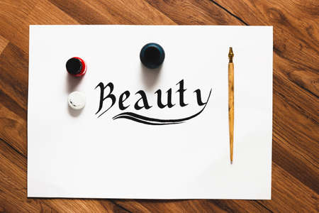 Calligraphy Beauty word background. Equipment and letters made with ink on white sheet top view. Painter workshop, small business inspiration, creativity concept.の写真素材