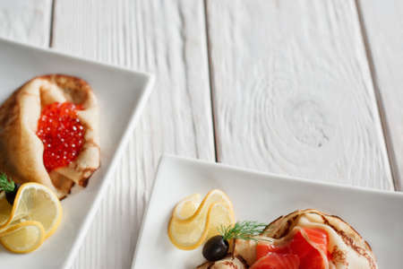 Set of dessert pancakes with seafood on white wooden background with free space. Russian traditional salty crepes with seafood. Shrove tuesday holiday foodの写真素材