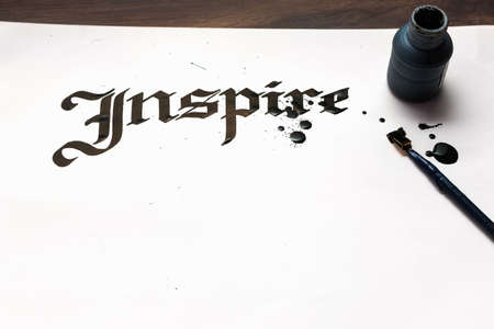 Inspire calligraphy . Artist workplace. Ink word on sheet of paper and pen top view. Drawing lessons, art school, creativity bacground conceptの写真素材