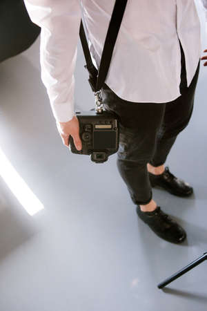 Unrecognizable photographer with camera. Man in studio holding professional photocamera.の写真素材