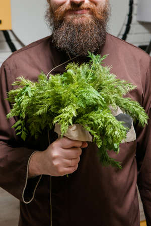 Chef with bouquet of dill and parsley, man with beard, cooking, green salad conceptの写真素材