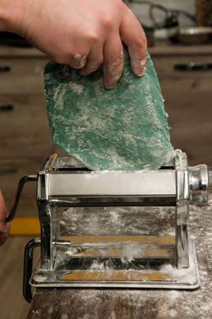 Chef with pasta machine do blue noodles dough. Colorful food concept closeup