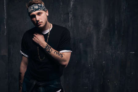 Dangerous tattooed gang member man stay on dark background. American gangster, dangerous people, urban style conceptの写真素材