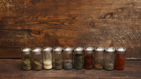 Colorful spices in jars on kitchen table. Wooden background with copy spaceの写真素材