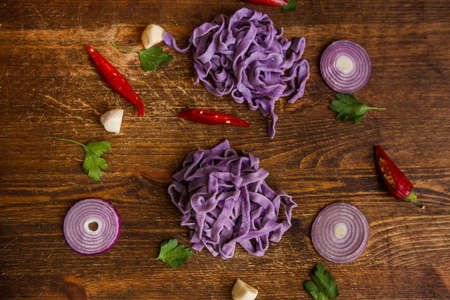 Colourful cooked fettuccine on table closeup. Violet tagliatelle with spices top view backgroundの写真素材
