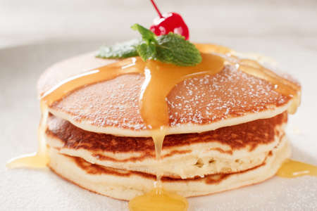 American pancakes with honey topping. Cooking food. Crepe with cherry on white plate background. Traditional US meal.の写真素材