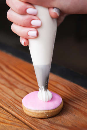 Gingerbread decorated by baker with cream. Colorful food, wedding present. Homemade cakes, bakery closeup conceptの写真素材