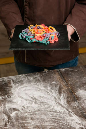 Unrecognizable chef on kitchen with color tagliatelle. Macaroni cooking process, background with free spaceの写真素材