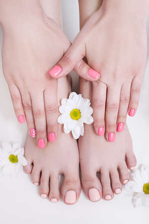 Nude manicure and pedicure for summer. Female hands and feet on white background top view. Result of spa salon procedureの写真素材