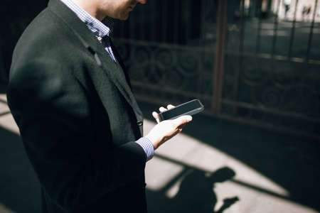 Modern communications. Business style, unrecognizable male with mobile phoneの写真素材