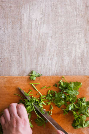 Cut into pieces batch of parsley on wooden desk. Herbs as healthy and organic food, top view of...