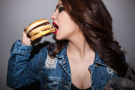 Closeup portrait of woman eating burger. Unhealthy diet of people and junk food conceptの写真素材