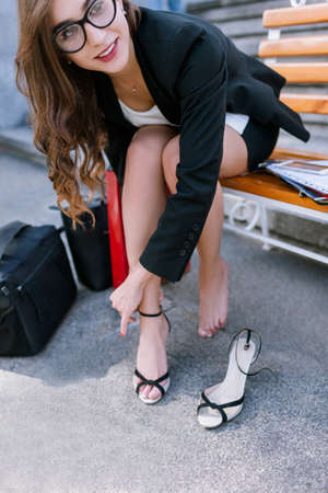 Barefoot young woman with tired legs. Confident and uninhibited girl taking off shoes, modern social behaviorの写真素材