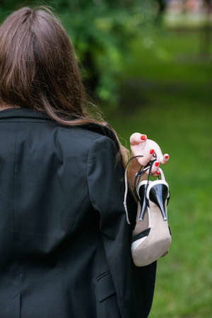 Self-confident woman walking without her shoes. Barefoot unrecognizable girl with tired legs closeup, modern social behaviorの写真素材