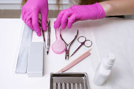 Workplace with manicure professional tools on white background. Nailcare instrument in beauticians hands top viewの写真素材