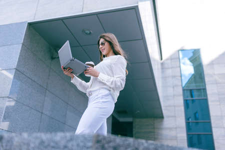 Successful young girl with laptop on coffee break. Social technology, urban street life, stylish...