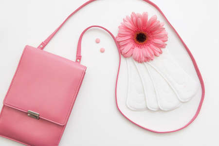 Contraceptive pills, white soft daily pads and flower with female pink bag, flat lay. Woman health, hormonal balance conceptの写真素材