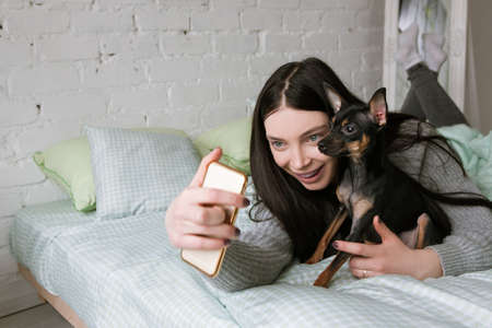 Friendship between dog and owner. Small puppy and lonely woman, girl take selfie with pet