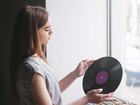 Girl choosing retro vinyl records in music shop. Modern hipster style, young female melomaniacの写真素材