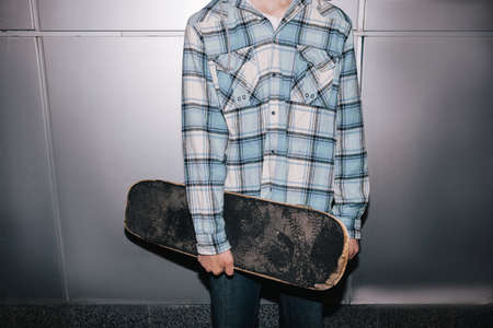 Skateboarder with skateboard. Street style. Modern youth closeup, subculture for young people, unrecognizable maleの写真素材