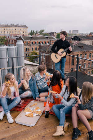 Party friends with junk food. Happy friendship with pizza, students celebrating outdoorsの写真素材