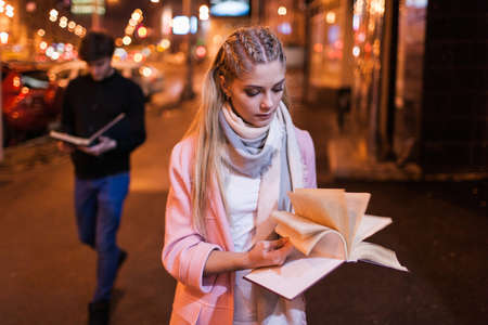 Bookworm on night street. Interesting reading. Student studying outside, search for information in textbookの写真素材