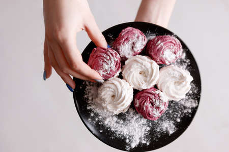 Colorful sweet zephyrs on black plate top view. Delicious confectionery and cookies temptation, homemade dessert for breakfastの写真素材
