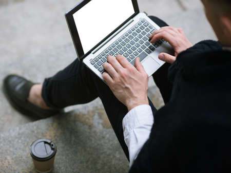 Social media communication. Technology for men. Remote work, unrecognizable businessman chatting outdoors top view, laptop with empty white screen mockupの写真素材