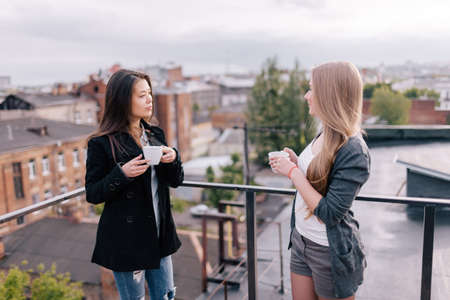 Female rivalry. Jealousy and gossips. Intense tea party, two girls on roofの写真素材