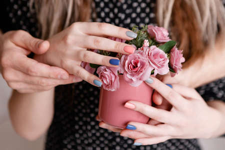 Man and woman holding roses in crimson cup together. Sensitive concept of gift with love, romantic proposal, close relationship between peopleの写真素材