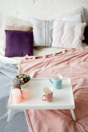 Breakfast in bed. Modern bedroom in pastel colors. Coffee and strawberries on small table decorated candles. Romantic concept and tendance between couples, close upの写真素材