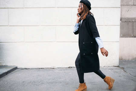 Fashion pedestrian. Modern social communications. Stylish black woman on white background, African American model, technology conceptの写真素材