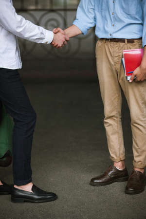 Businessmen meeting, handshake and closing deal. Stylish male students. Unrecognizable men, modern youth, education conceptの写真素材