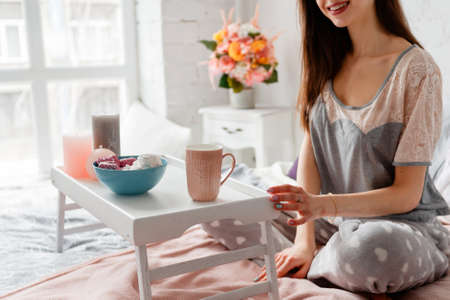 Smiling woman has breakfast in the morning. Good start of the day, enjoyment and calmness, comfort...
