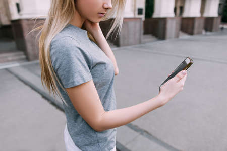 Modern communication in real life. Girl with gadget, young blonde with mobile phone on street
