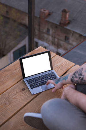 Modern communication. Laptop with white screen. Social media connection, unrecognizable male typing on computer outdoors. Freelance work outside, dating service, information search, technology conceptの写真素材