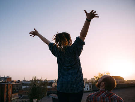 Freedom life. Relief from problems on roof. Unrecognizable hipsters watching sunset, urban background with free space, romantic dateの写真素材