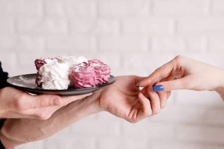 Man proposes zephyrs on plate to woman. Sensitive background with free space, gift with love, romantic present, tenderness in relationship conceptの写真素材