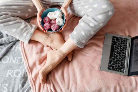 Young woman holds teal plate with zephyrs in hands. Delicious confectionery and gourmet cookies combining with social life and working, top viewの写真素材