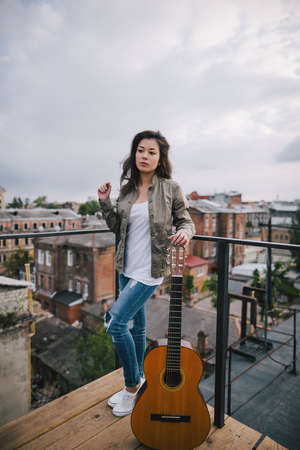 Street music. Young girl with acoustic guitar on city roof. Freedom, leisure, youth lifestyle, young...