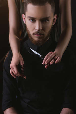Hipster young male cutting hair portrait. Handsome modern man closeup, unrecognizable female hairdresser with tools, fashion look, beauty conceptの写真素材