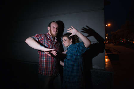 Caught hipster criminals. Forbidden relationships. Young couple on night street, adultery, bright...