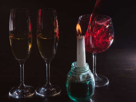 Romantic atmosphere alcohol on black background. Red wine pouring in glass motion advertising. Love date with candle backdrop closeup, romanticism conceptの写真素材