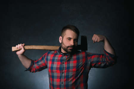 Strong woodsman with axe. Male strength. Muscular adult man on dark background, confident lumberjack portrait closeup, force conceptの写真素材