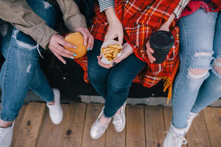 Takeaway junk food in meeting close friends. Top view unrecognizable stylish girls spending good time together. Rest and entertainment, leisure with cheerful atmosphere conceptの写真素材
