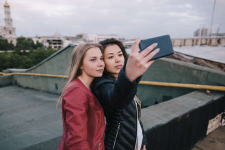 Selfie of two young girls on city background. Spending good time together on roof, unusual places...