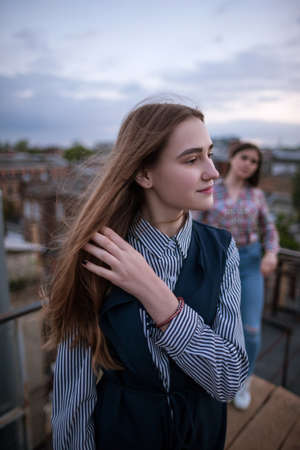 Young blonde with friend on cloudy sky background. Sisters, family, friendship relationships conceptの写真素材
