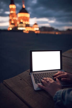 Hands typing on blank laptop at city night background. Communication in a social network, shopping online, remote work conceptの写真素材