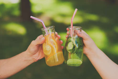 Friends celebrate with detox juice cocktailss on green nature background witn free space. Diet on the go, well being and weight loss, superfoods, health, vegetarian food conceptの写真素材